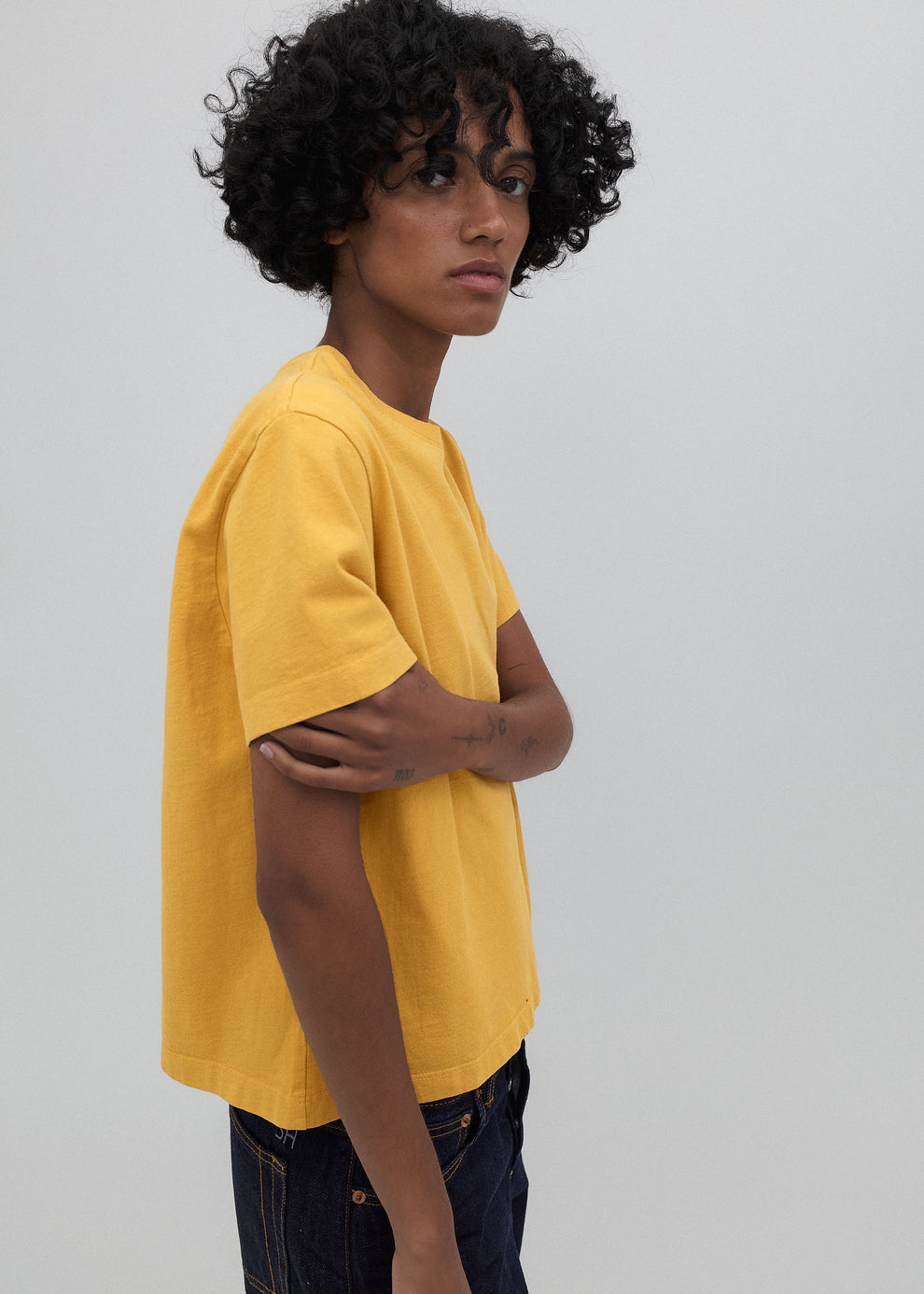 Person wearing a yellow t-shirt against a plain background