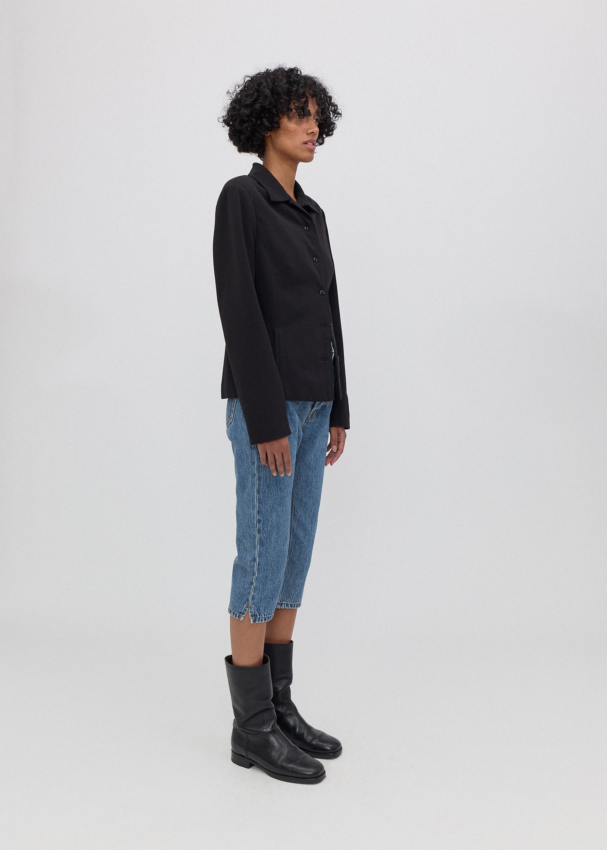 Person wearing a black jacket, blue jeans, and black boots on a white background