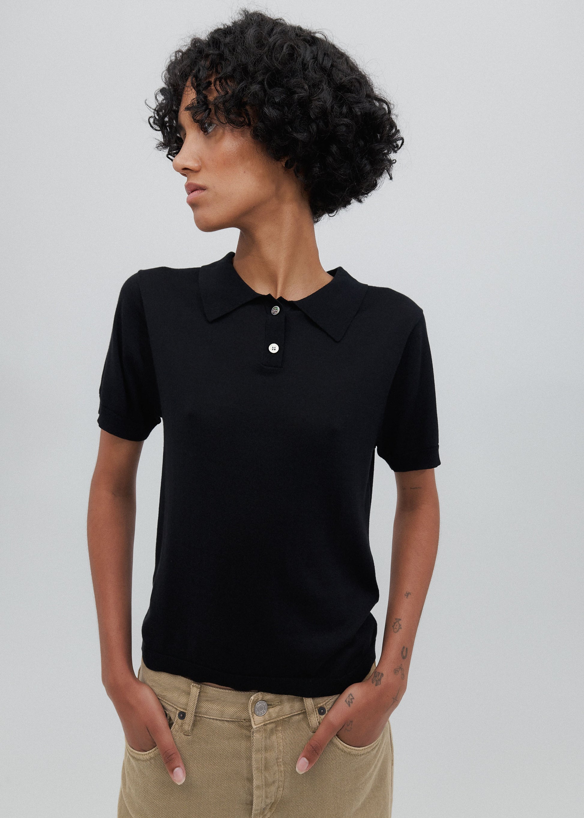 Woman wearing a black polo shirt against a plain background