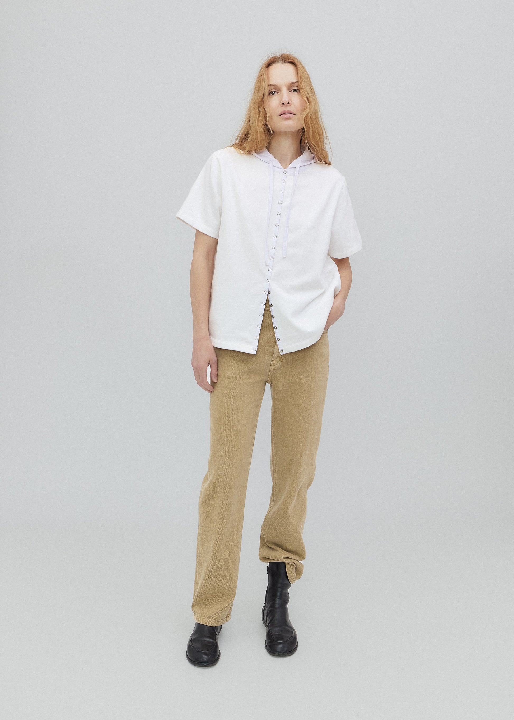 Person wearing a white shirt and beige pants on a plain background