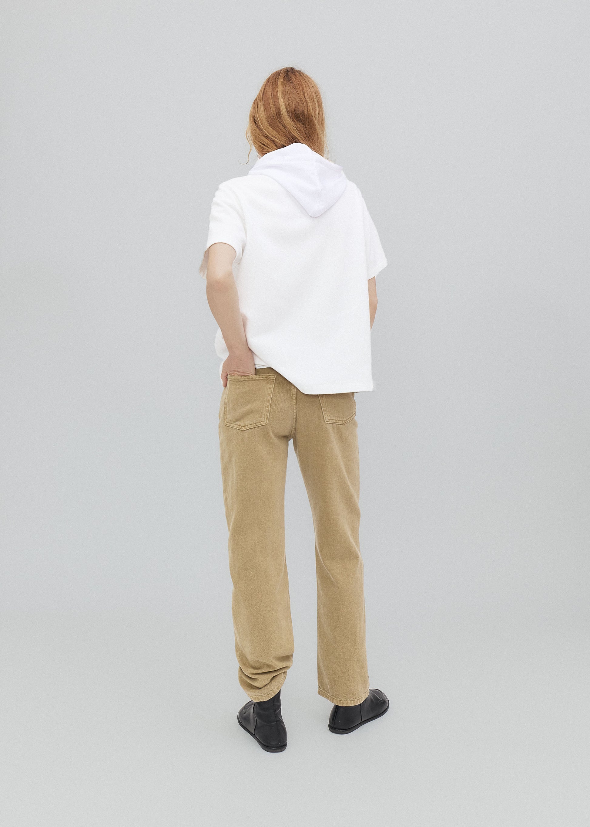 Person wearing a white hoodie and beige pants on a plain background