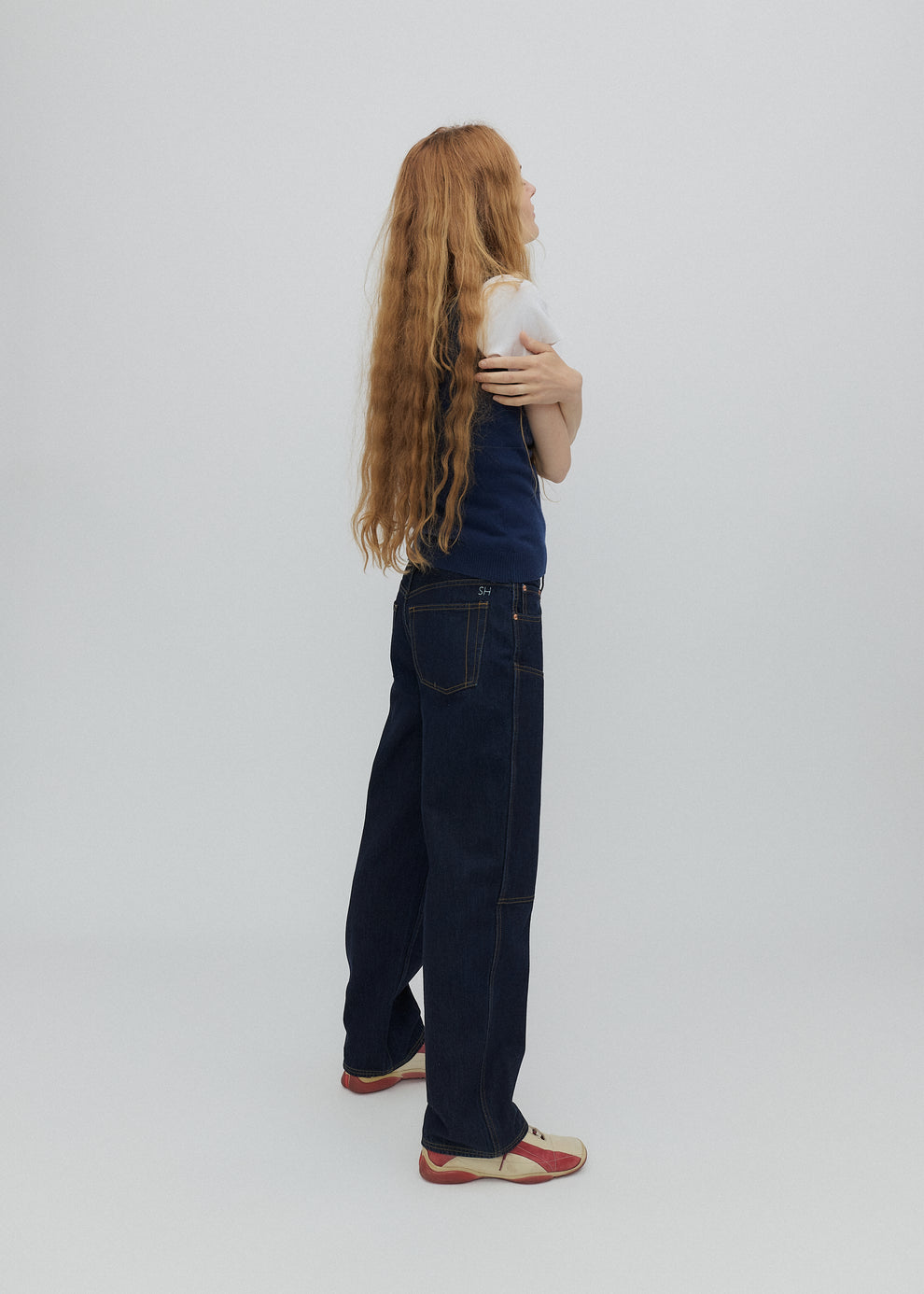 Person wearing dark blue jeans holding a phone on a plain background
