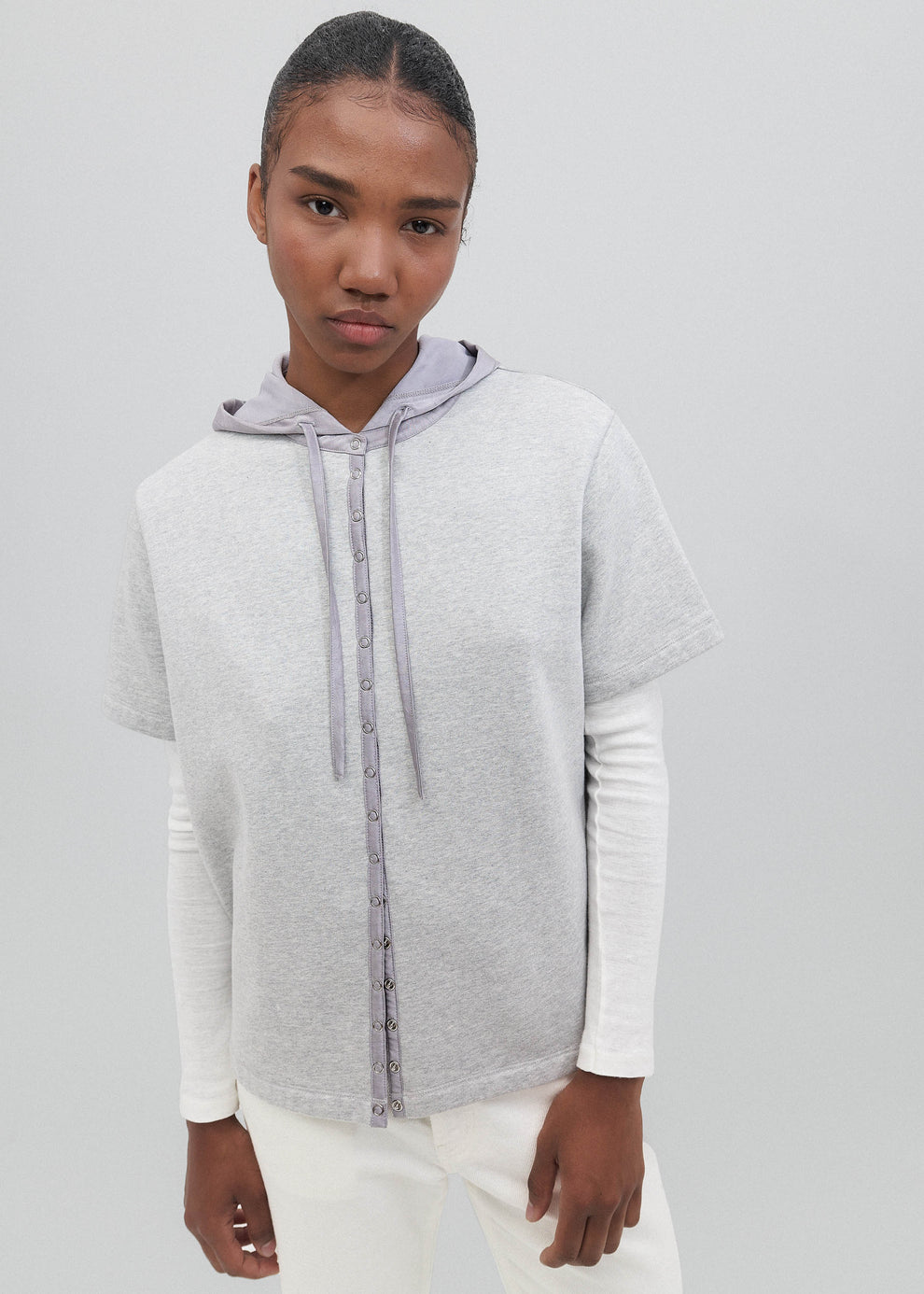 Person wearing a gray and white hoodie on a plain background