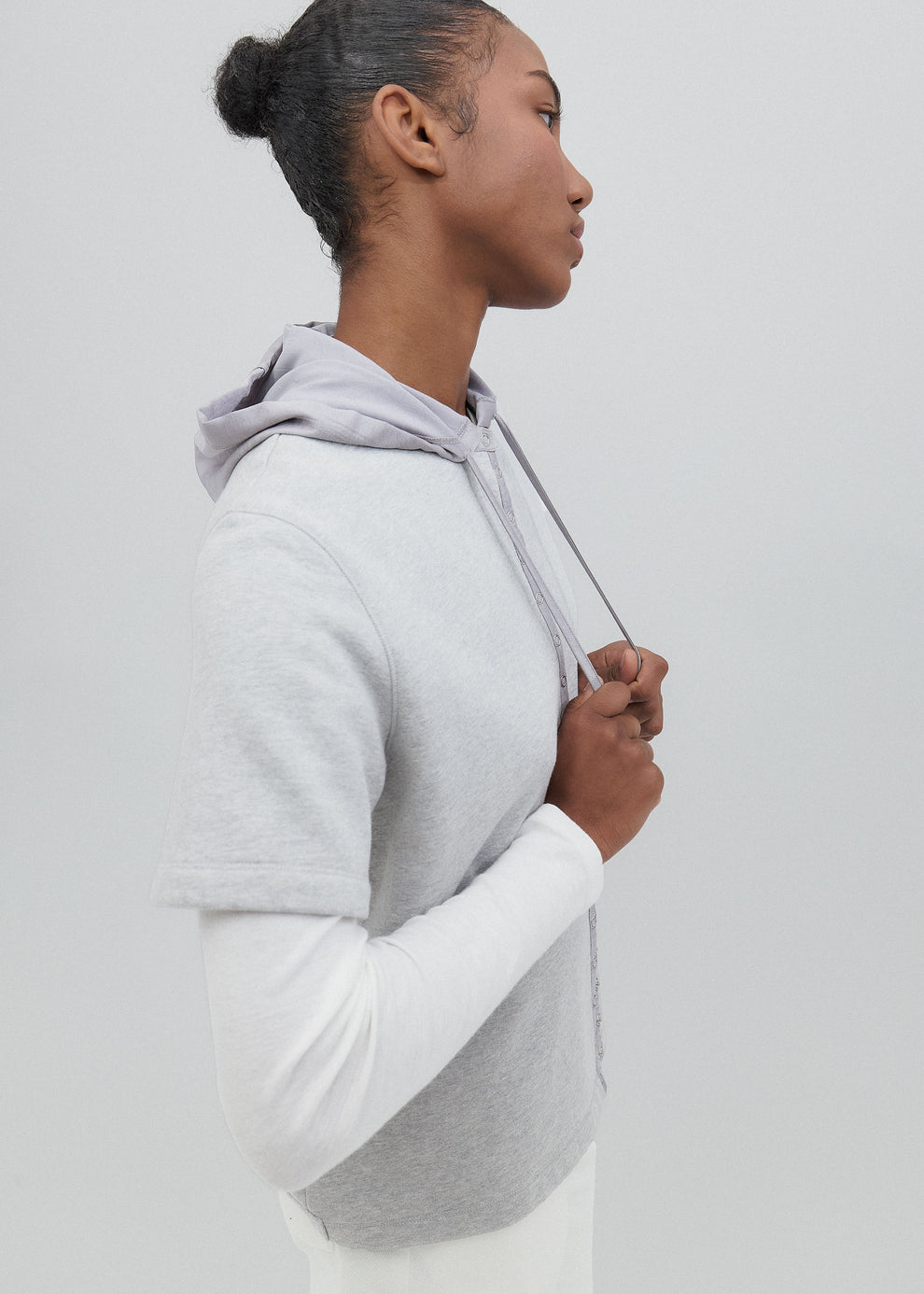 Person wearing a gray and white hoodie against a plain background