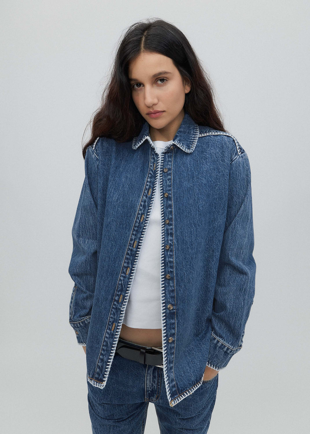 Woman wearing a blue denim jacket on a plain background