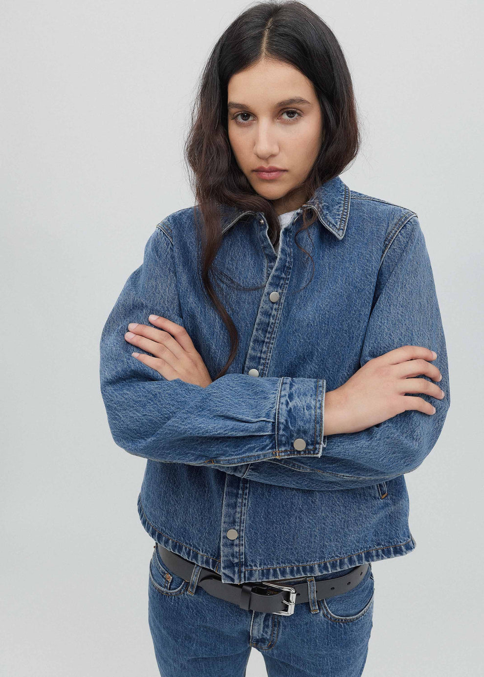 Woman wearing a blue denim jacket against a plain background