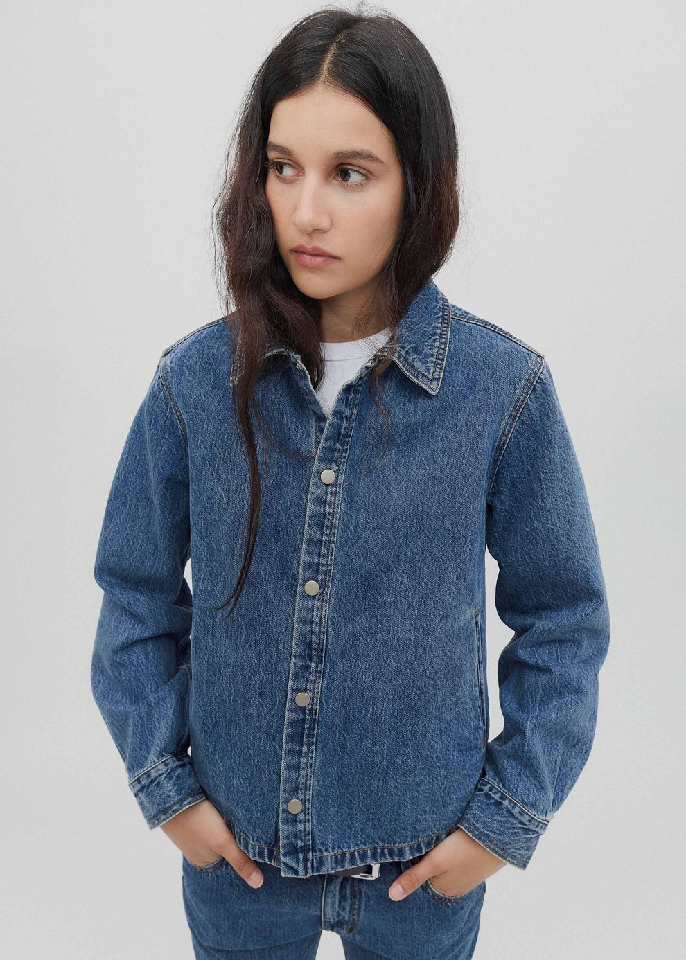 Person wearing a blue denim jacket on a plain background