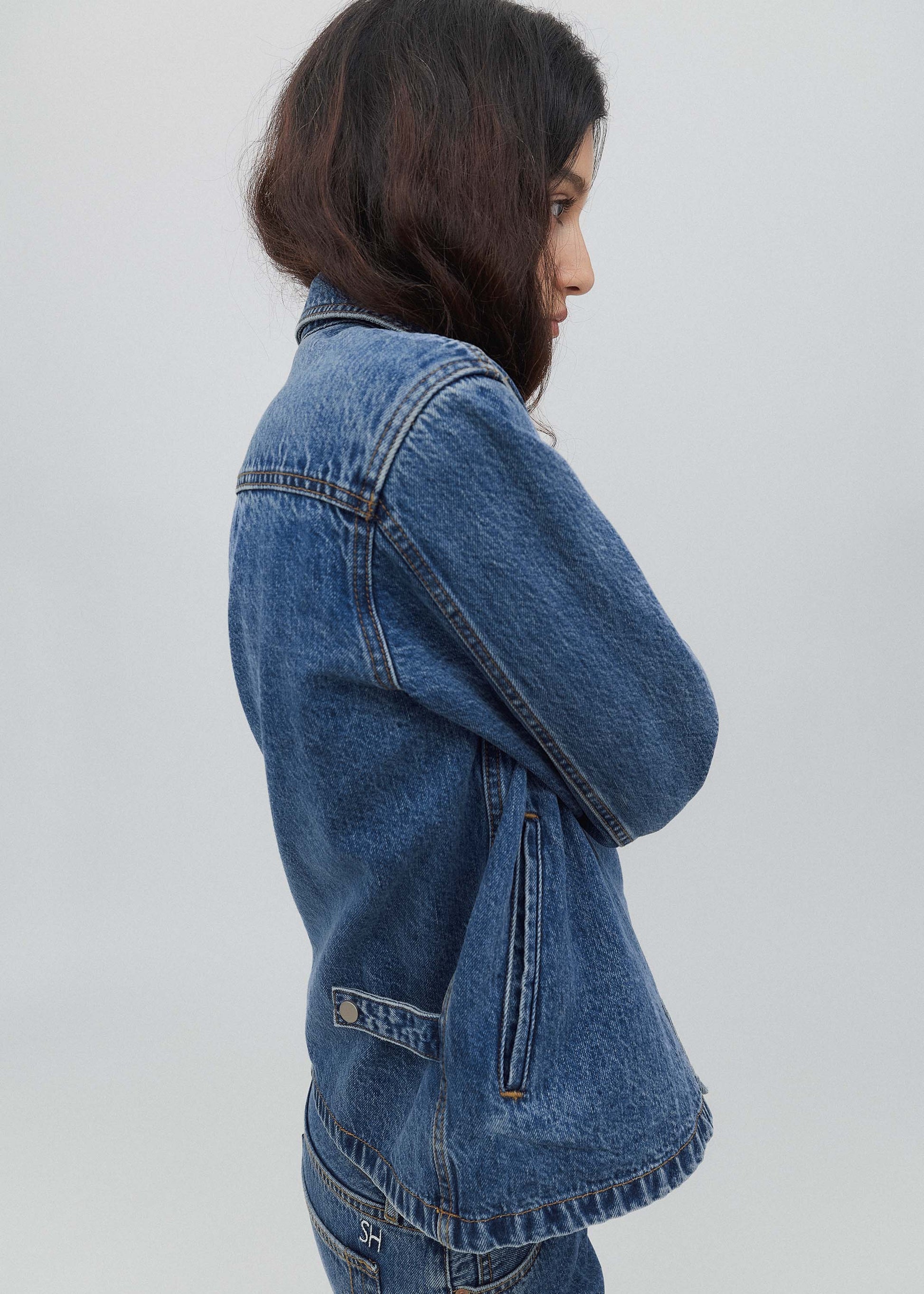 Person wearing a blue denim jacket on a plain background