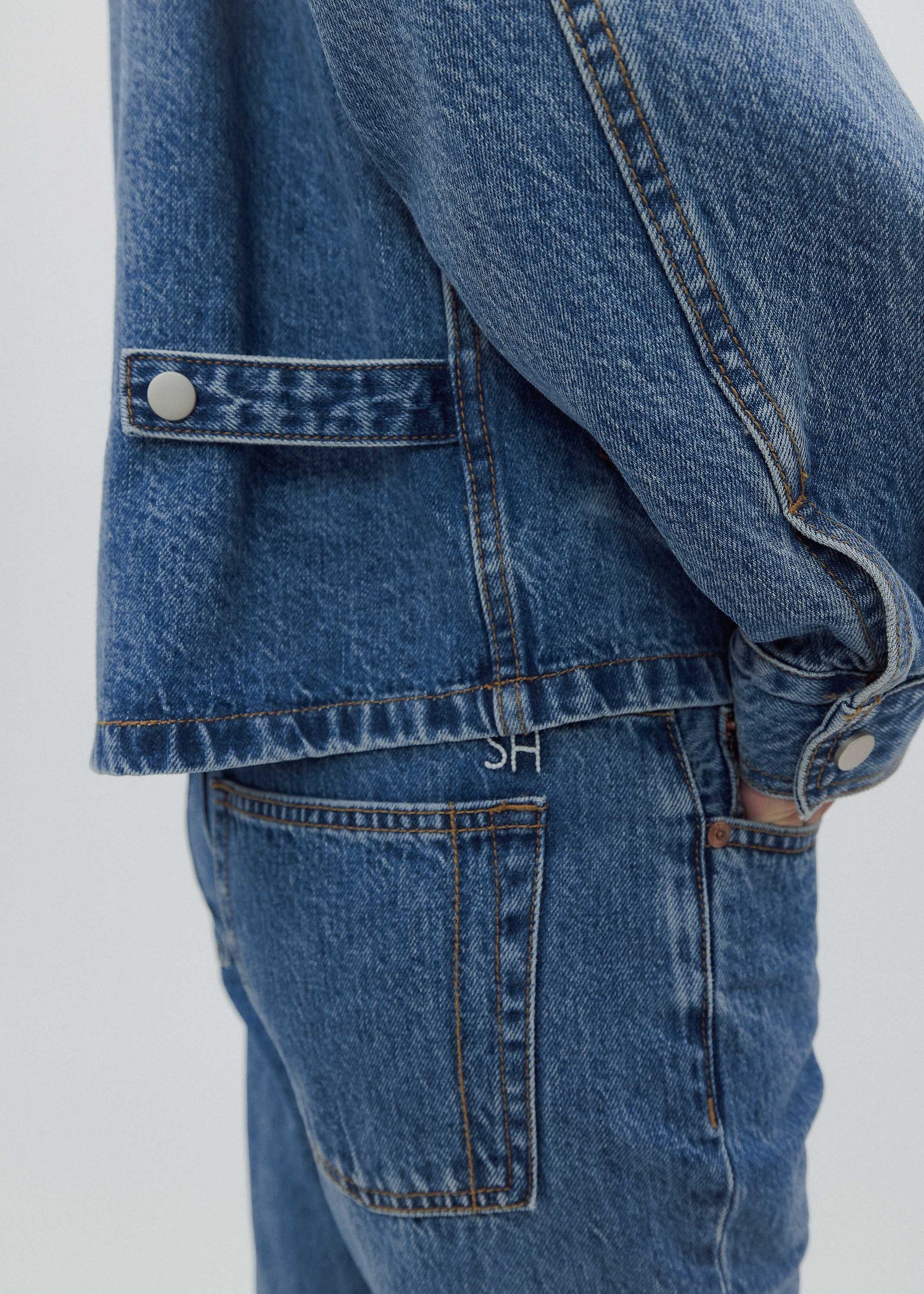 Close-up of a blue denim jacket and jeans on a white background