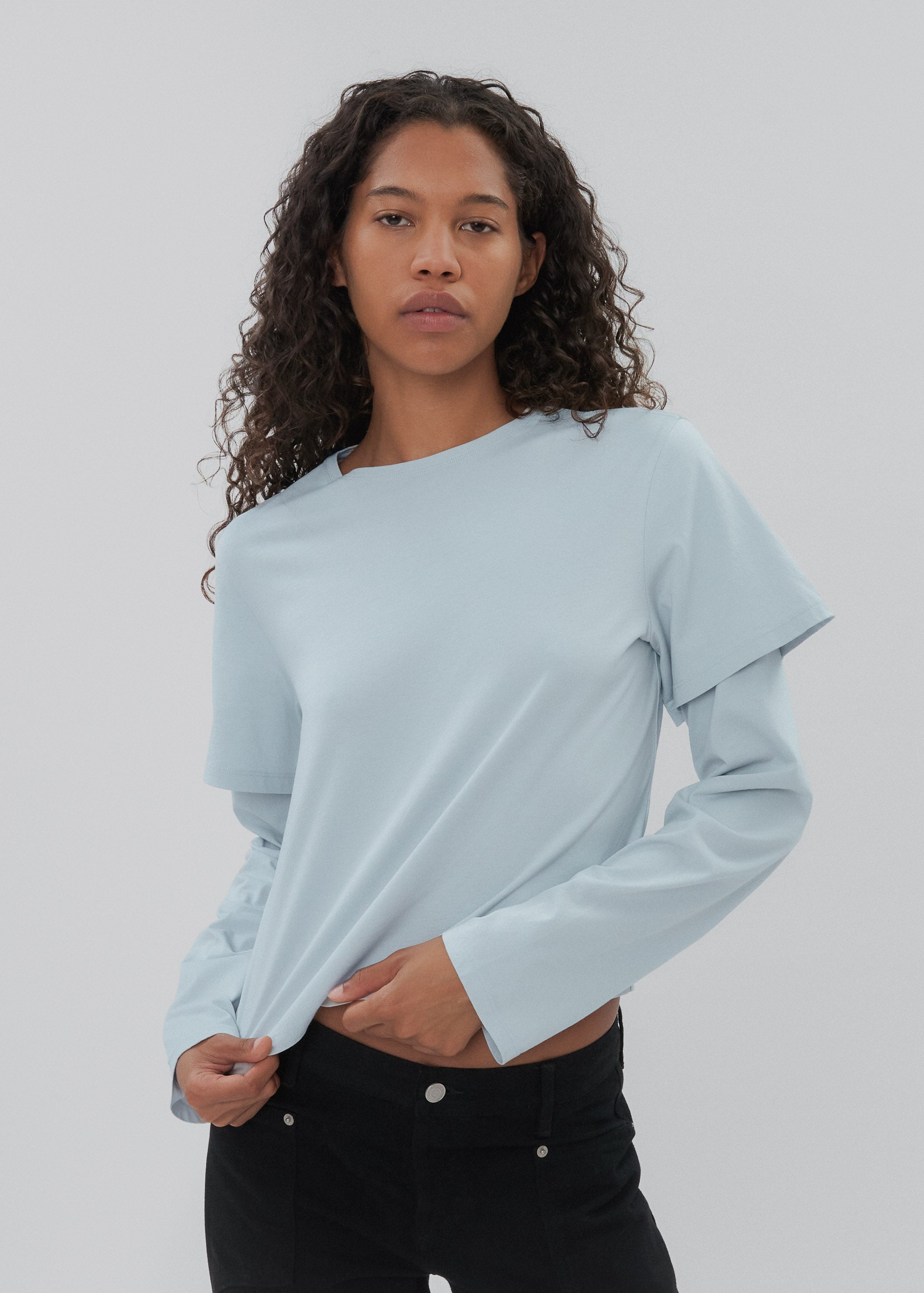 Woman wearing a light blue long-sleeve top against a plain background