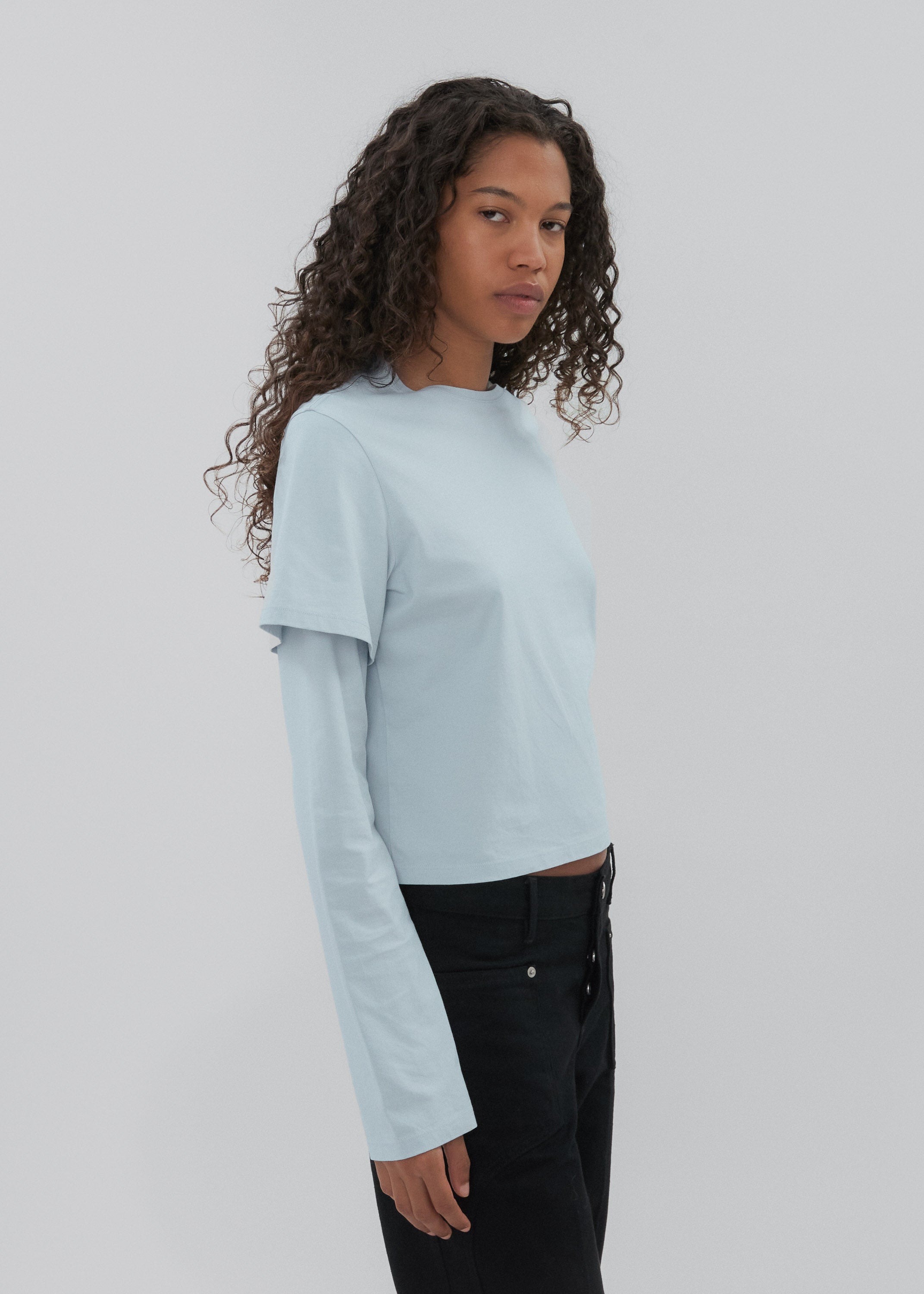 Woman wearing a light blue long-sleeve top against a plain background