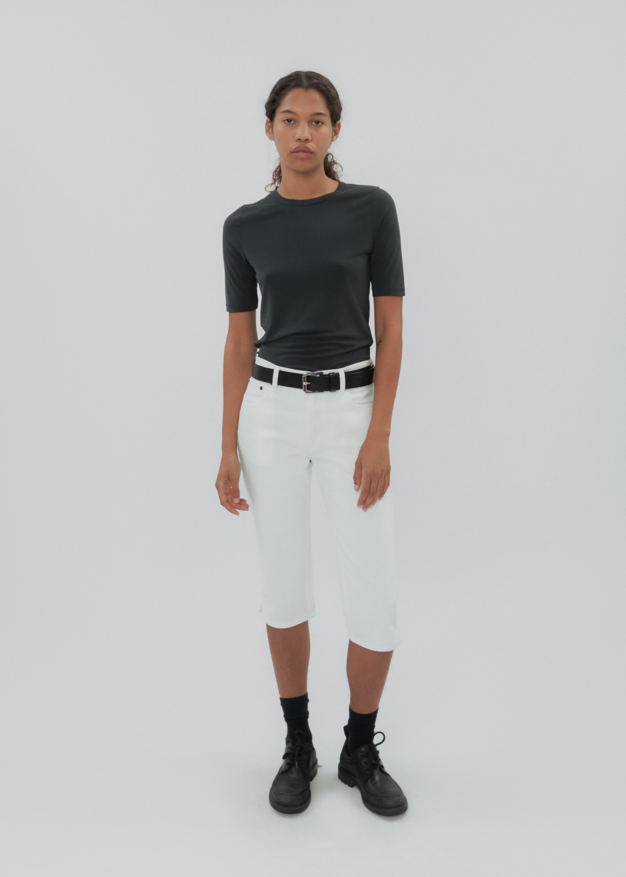 Person wearing a black top and white pants on a plain background