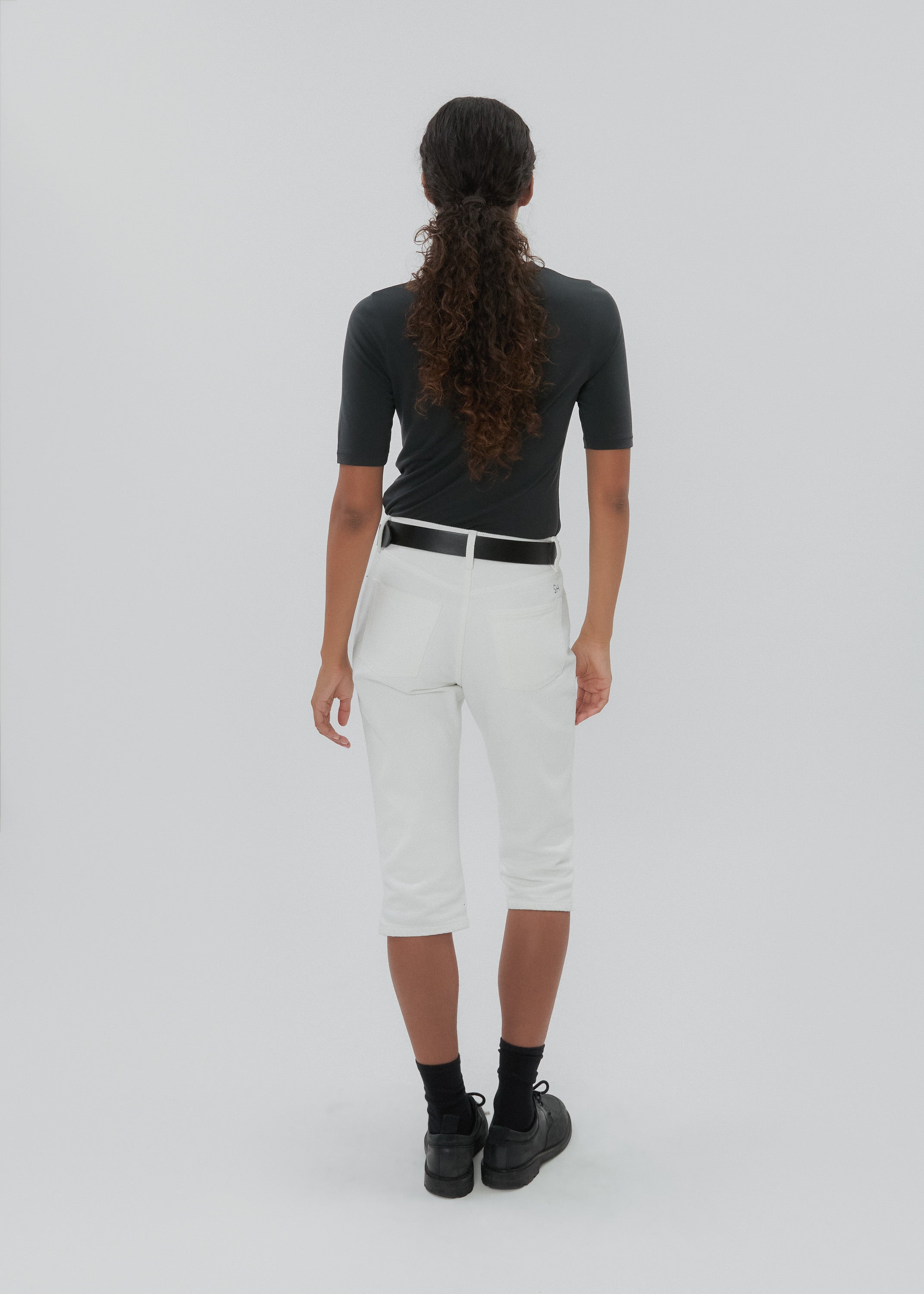 Person wearing a dark gray top and white pants on a light gray background