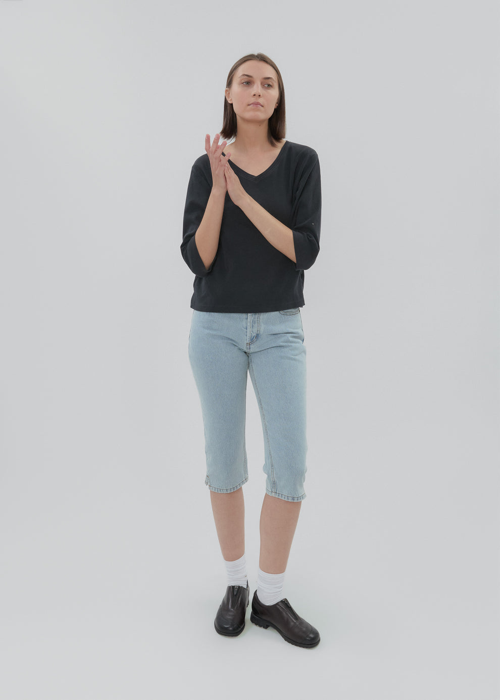Person wearing a black shirt, light blue jeans, and black shoes on a white background