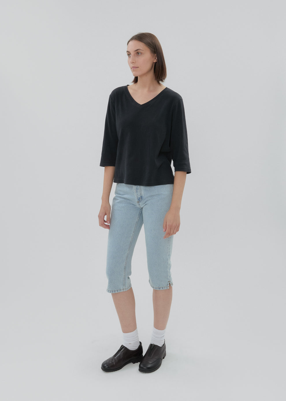 Woman wearing a black top and light blue jeans on a white background