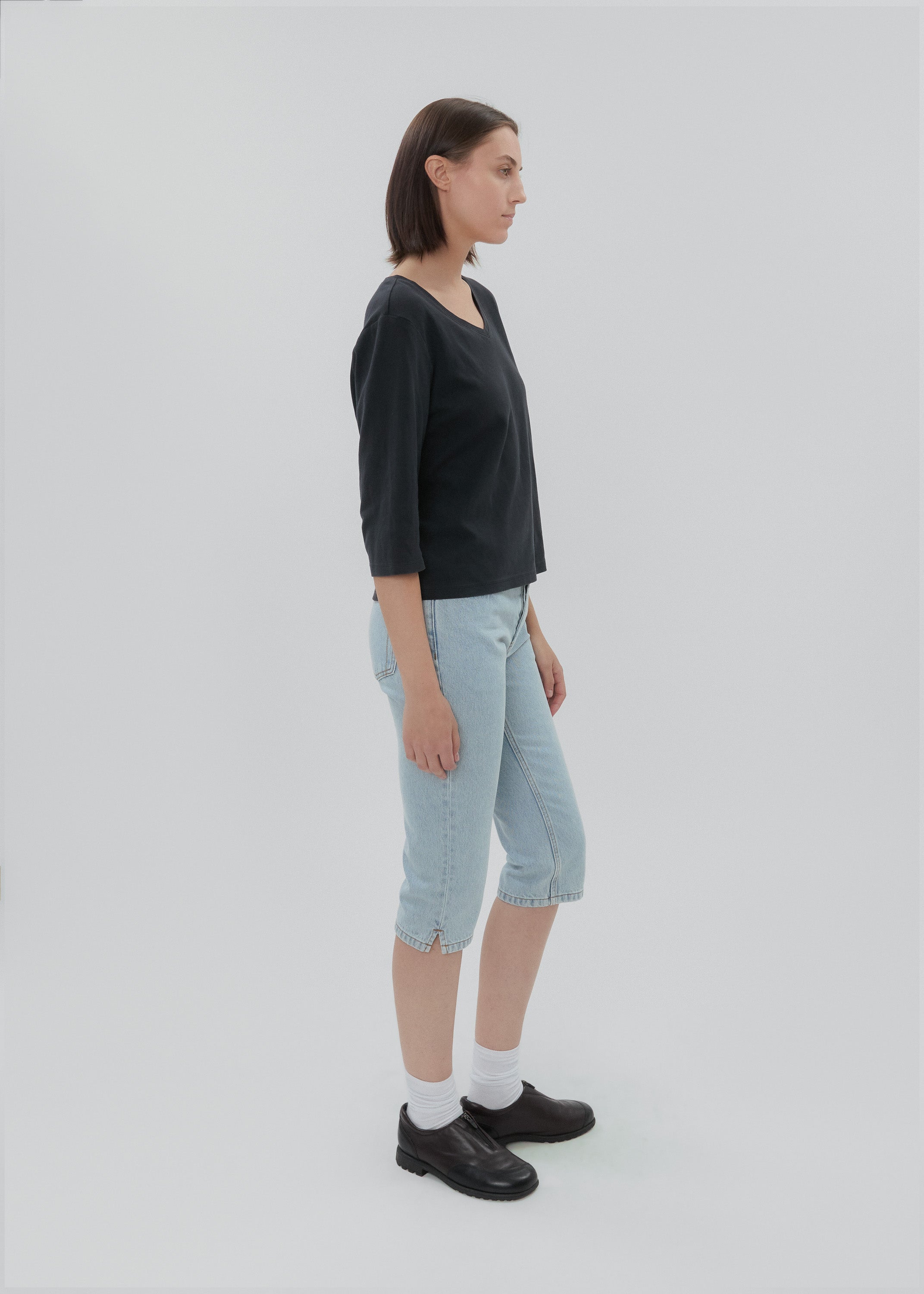 Person wearing a black top and light blue jeans on a white background
