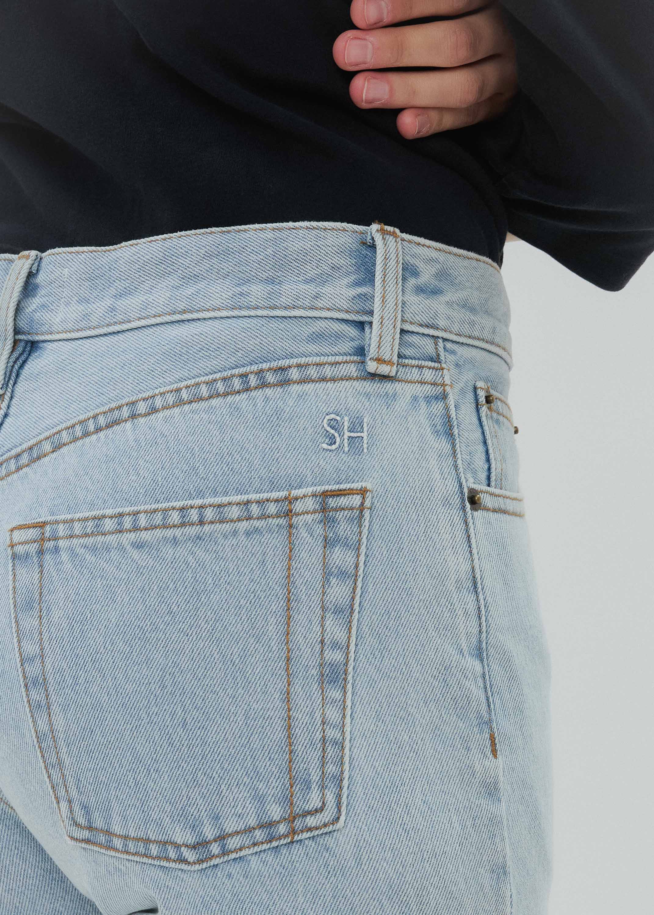 Light blue jeans with a brand logo on the pocket against a plain background