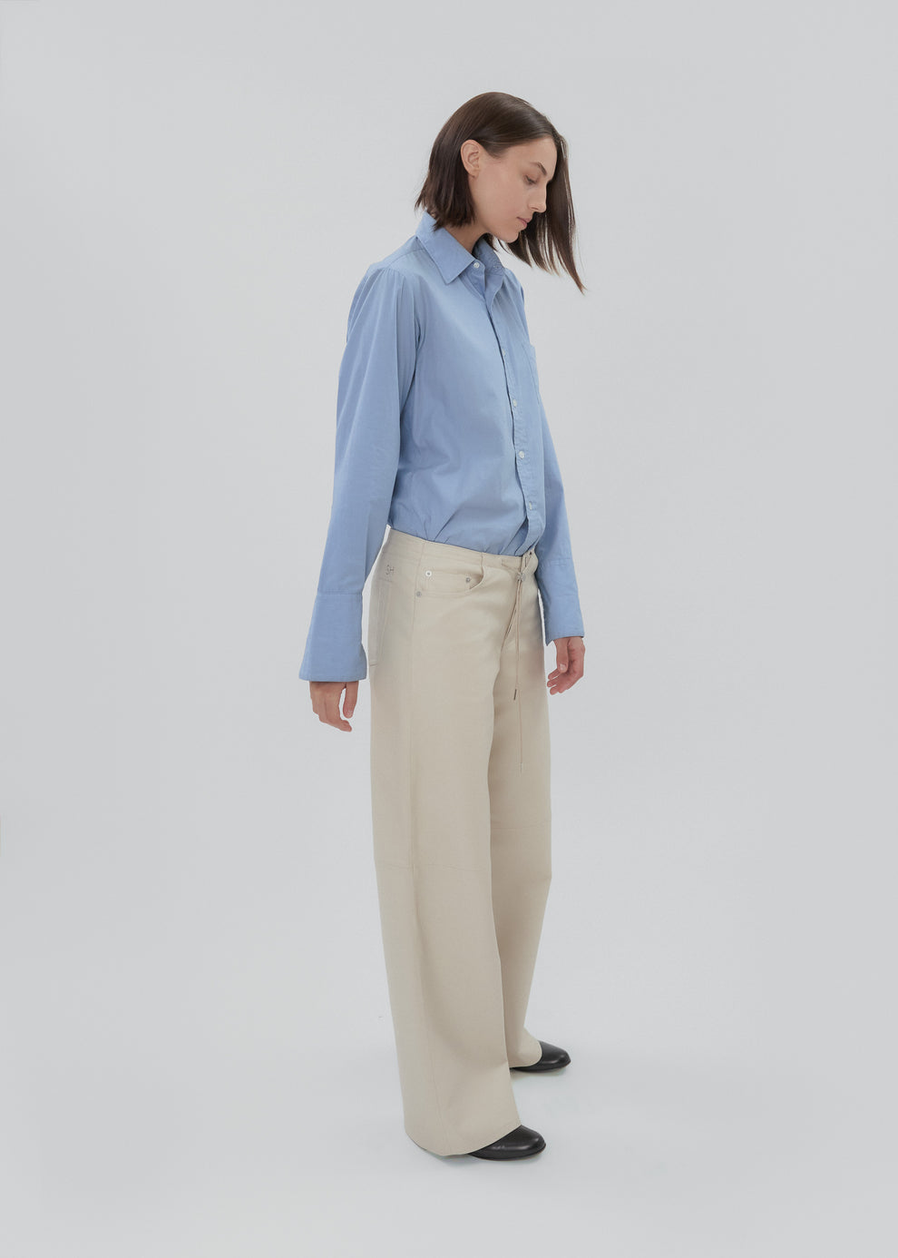 Woman wearing a light blue shirt and beige pants on a white background