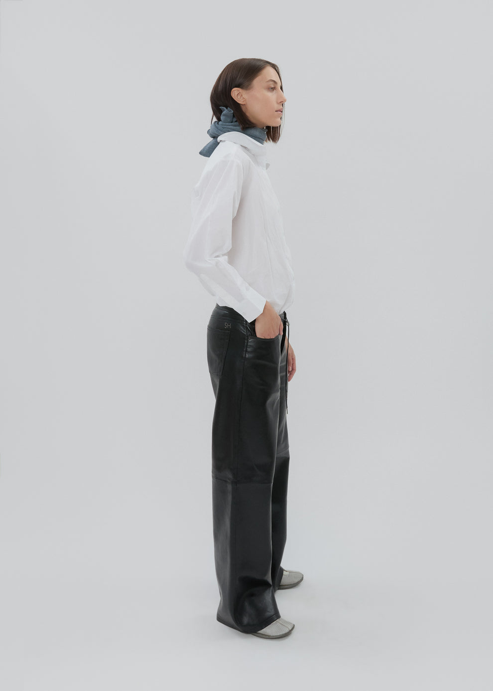 Person wearing a white shirt and black pants on a light gray background