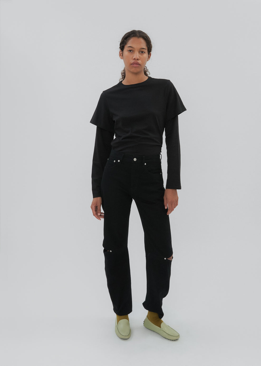 Person wearing a black long-sleeve shirt and black pants on a white background