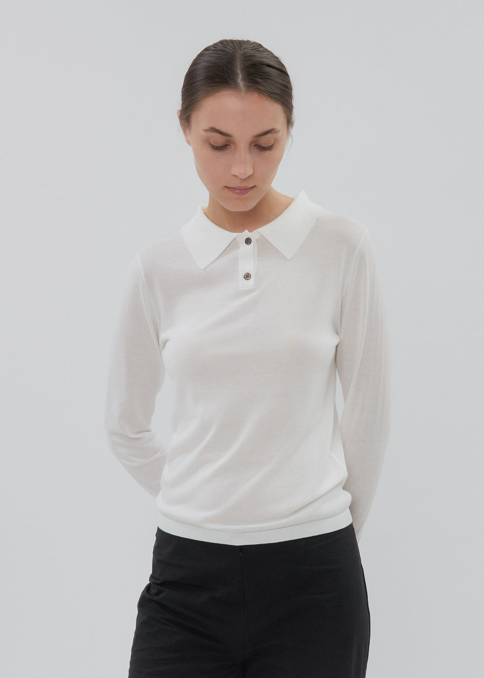 Woman wearing a white long-sleeve polo shirt against a plain background