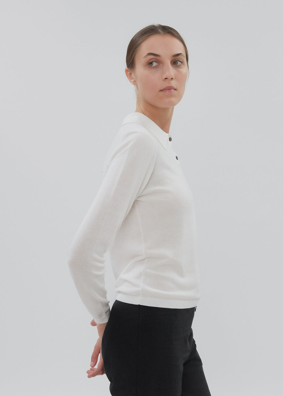 Woman wearing a white long-sleeve shirt against a plain background