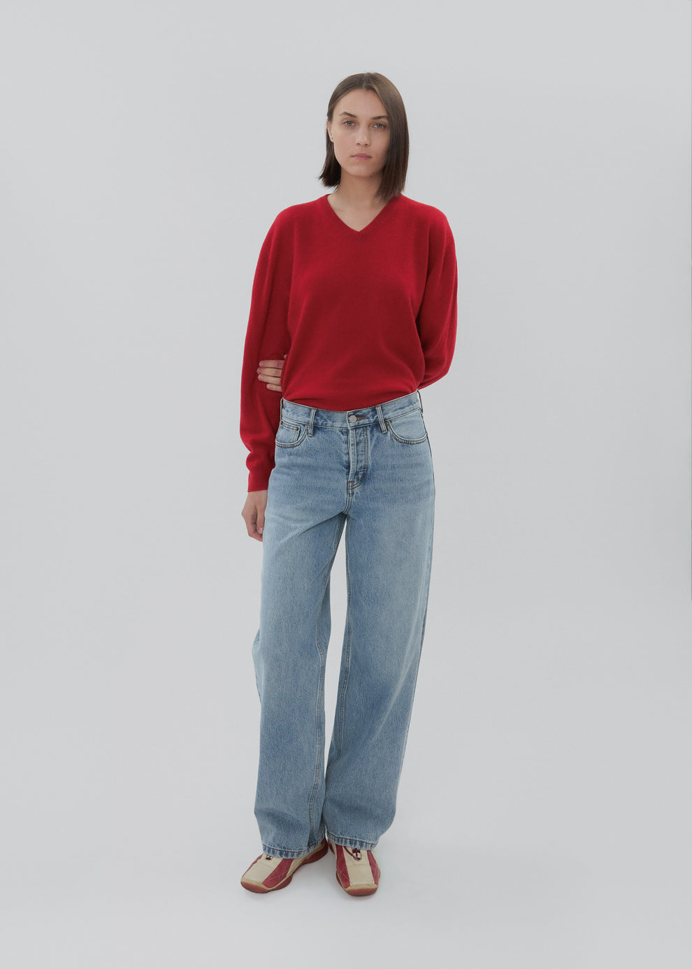Person wearing a red sweater and blue jeans on a white background