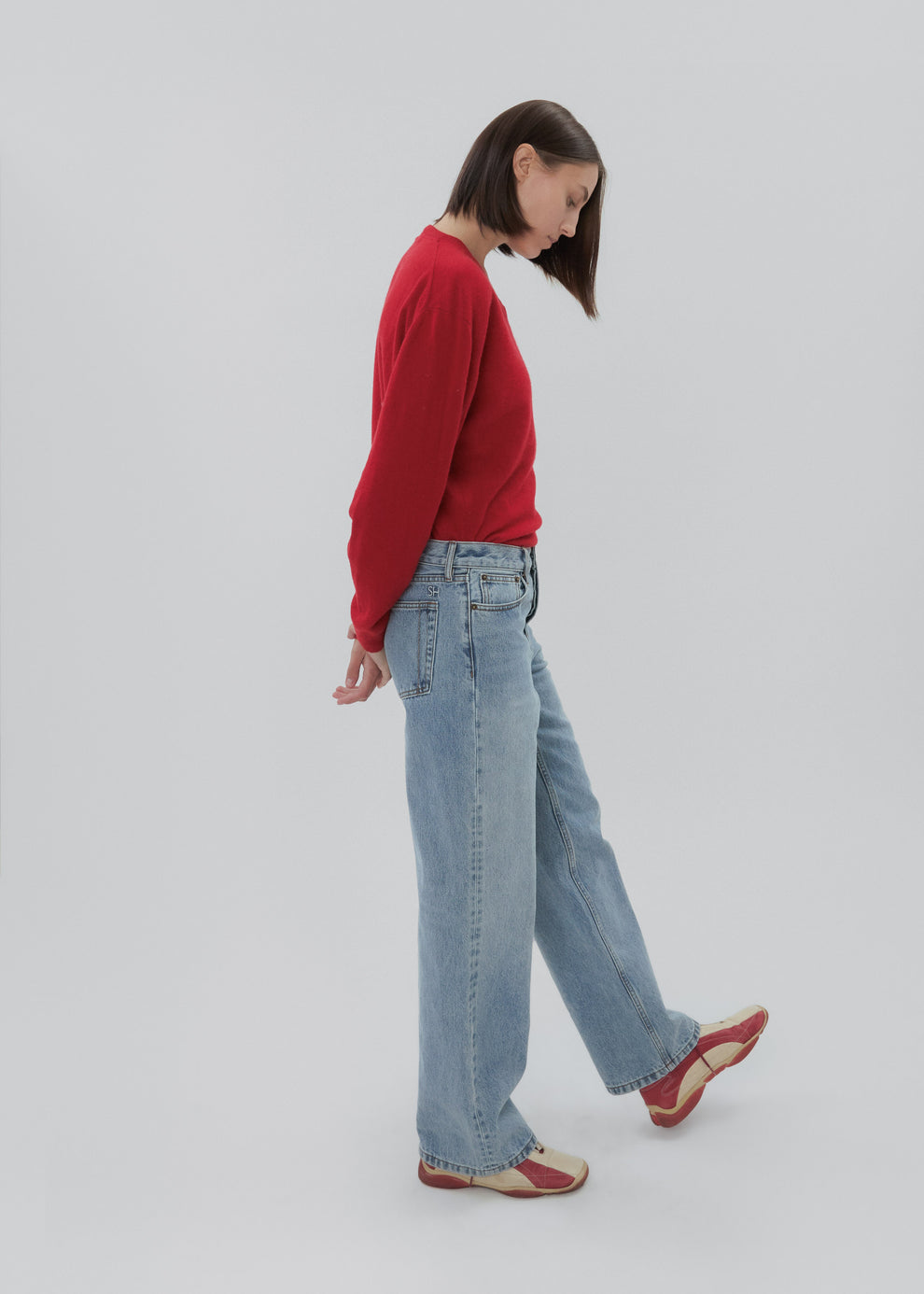 Person wearing a red sweater and blue jeans on a plain background