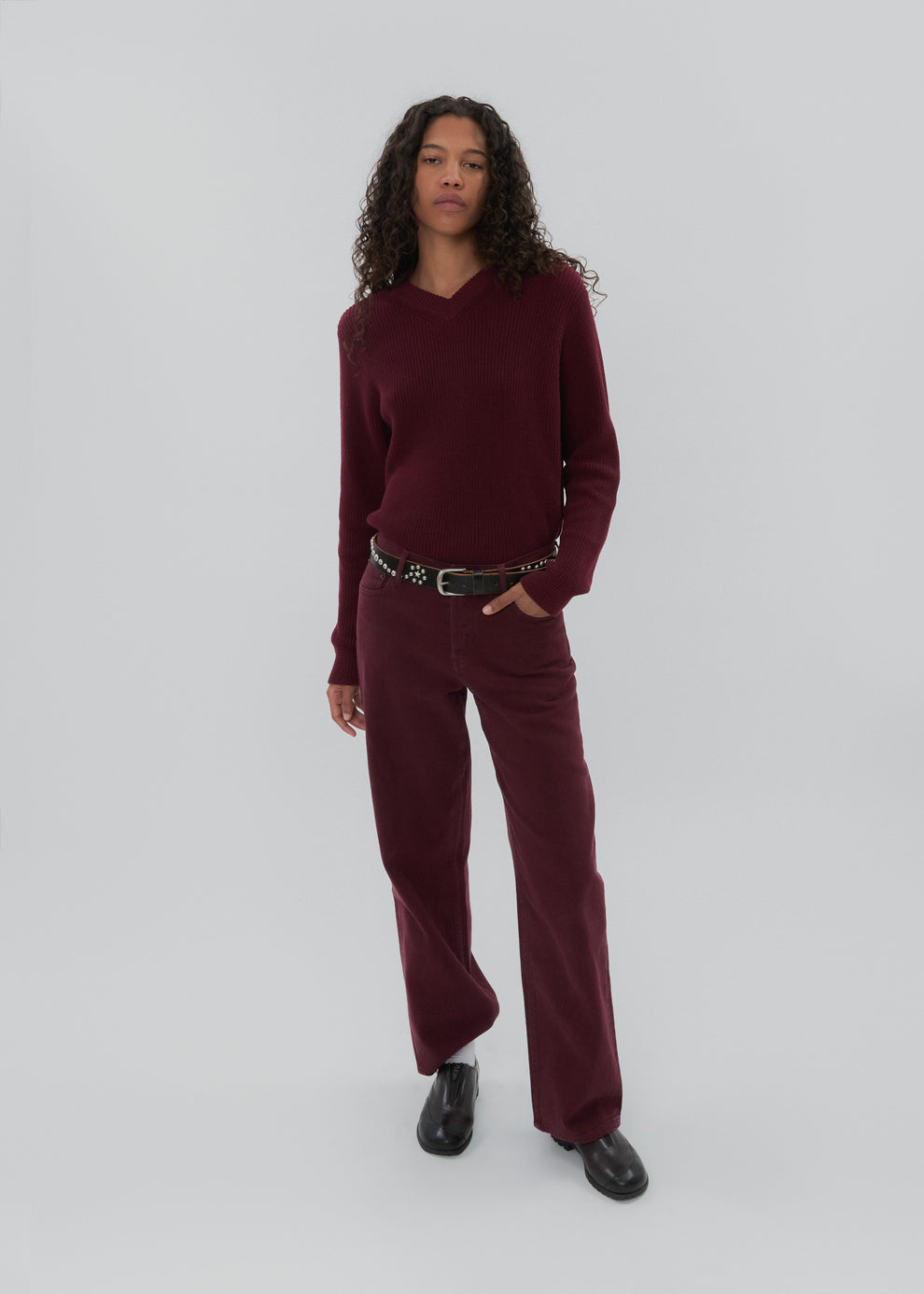 Person wearing a burgundy sweater and pants on a white background