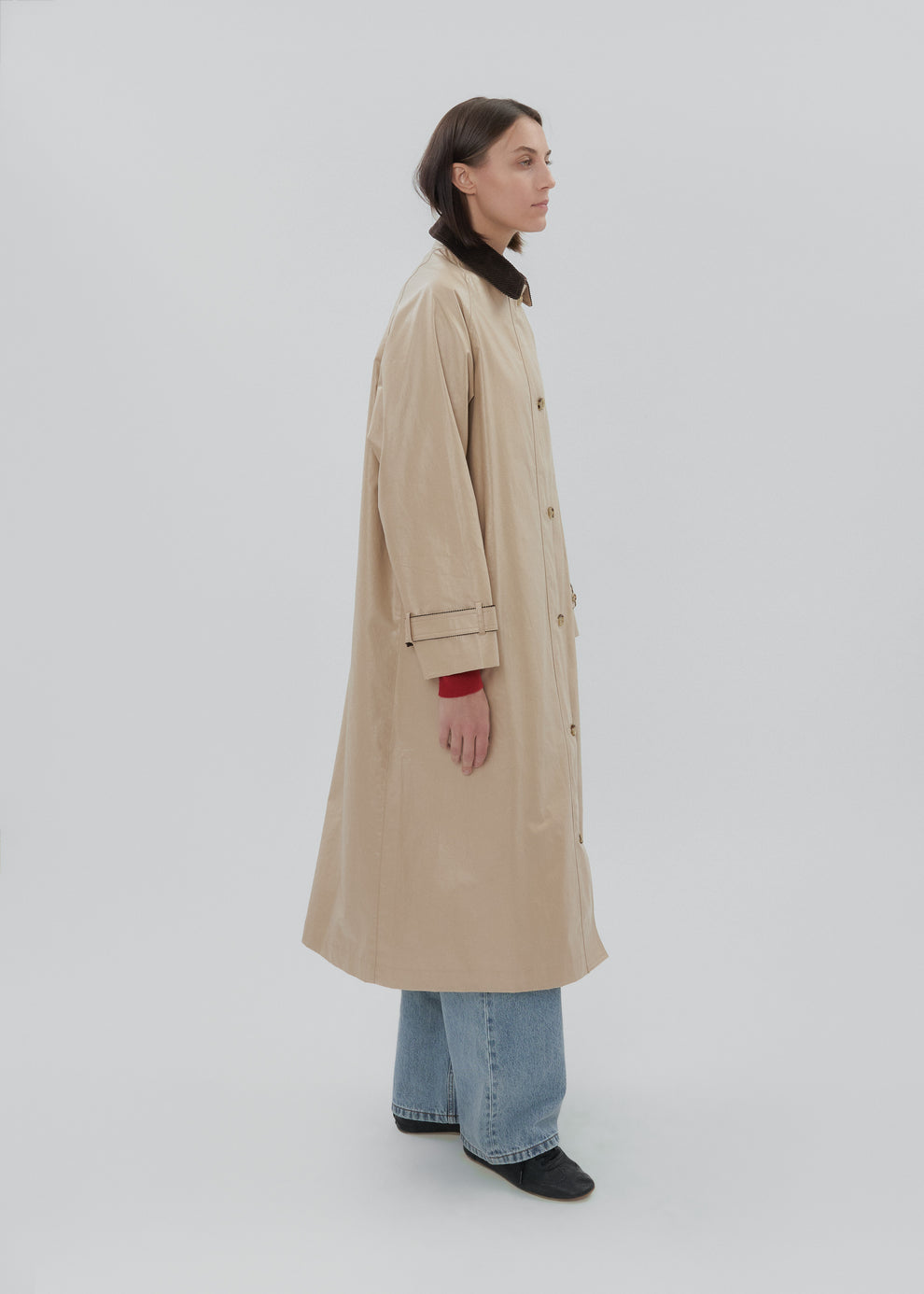 Person wearing a beige trench coat on a white background