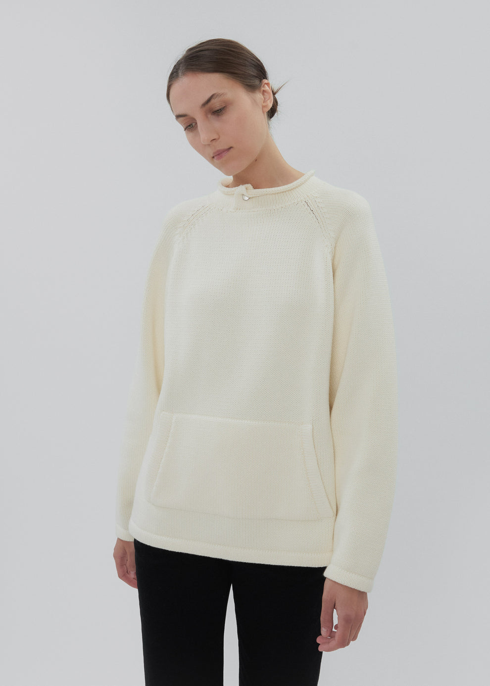 Woman wearing a cream-colored sweater against a white background