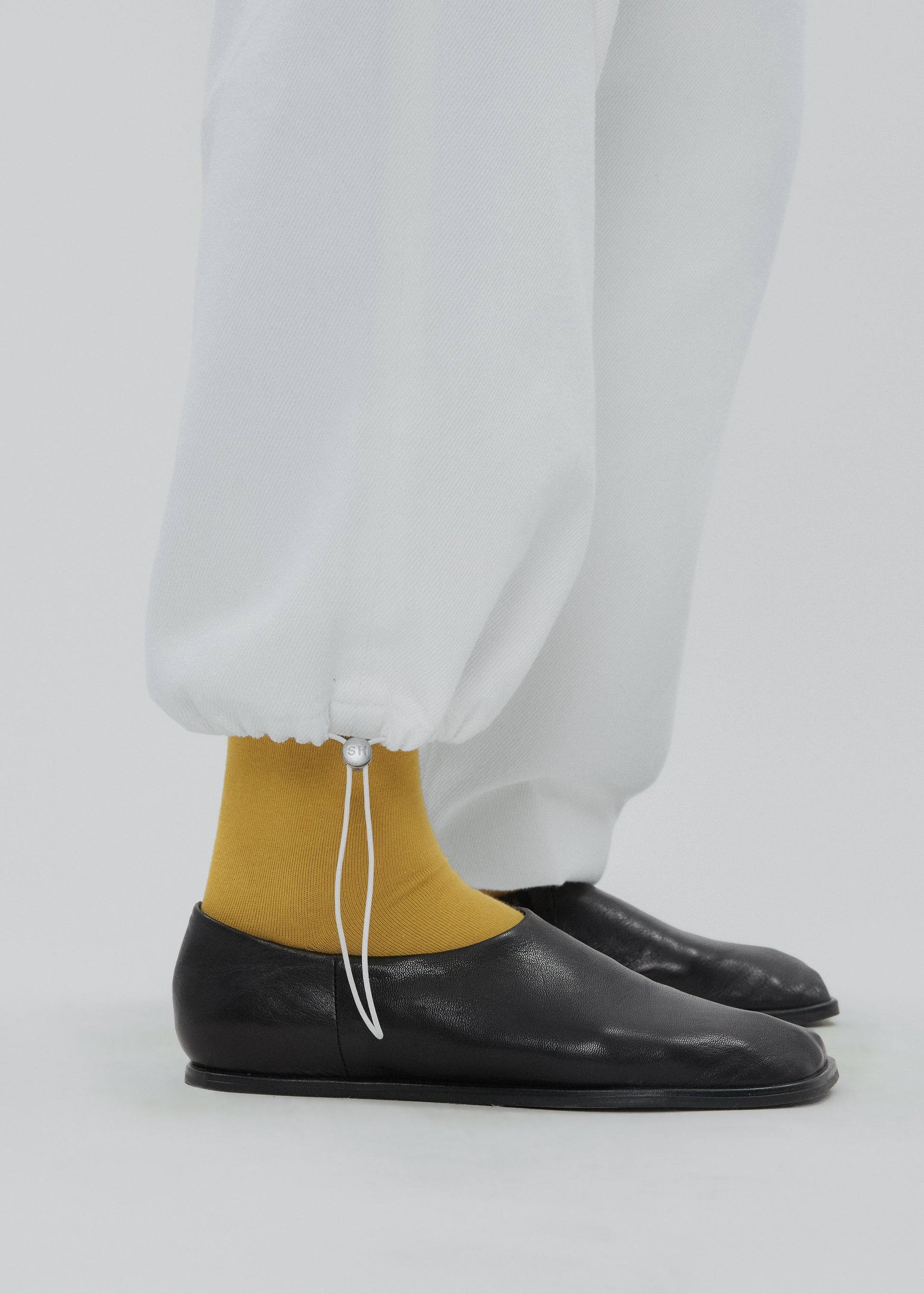 Person wearing black shoes and mustard yellow socks with a white background