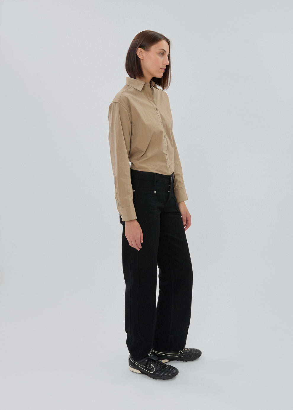 Woman wearing a beige shirt and black pants on a white background