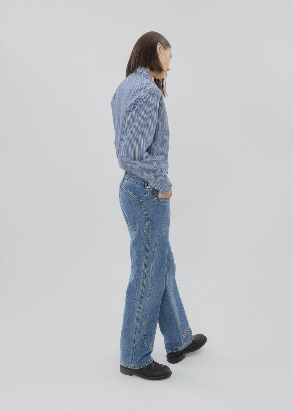 Person wearing a blue shirt and jeans on a white background