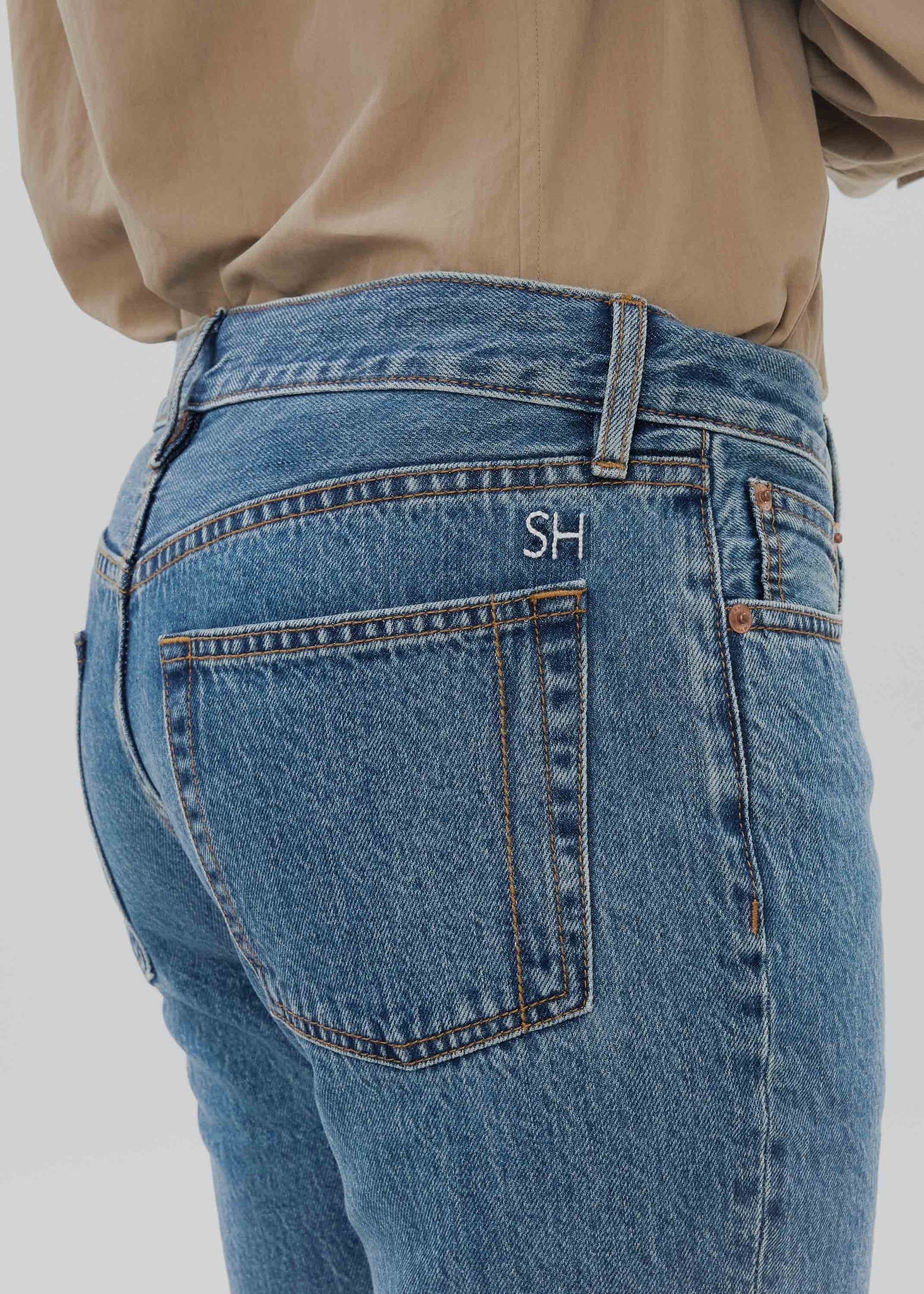 Blue jeans with a brand logo on the pocket against a neutral background