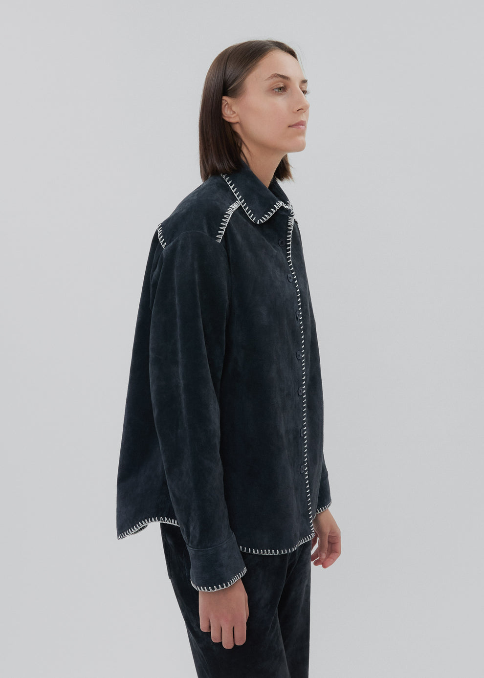 Person wearing a dark gray jacket with white trim on a light gray background