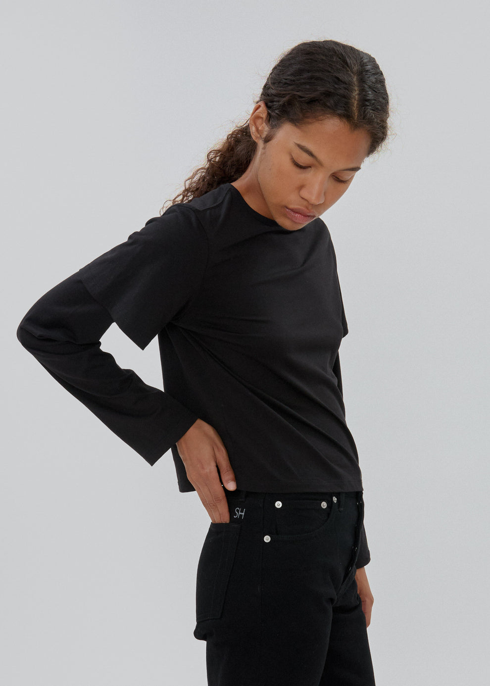 Person wearing a black long-sleeve top and black pants on a plain background