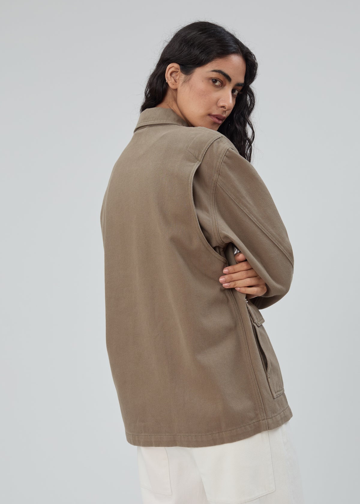 A person viewed from the back wearing an olive green cotton Barn Jacket in Army Green with a collared neckline and side pockets.