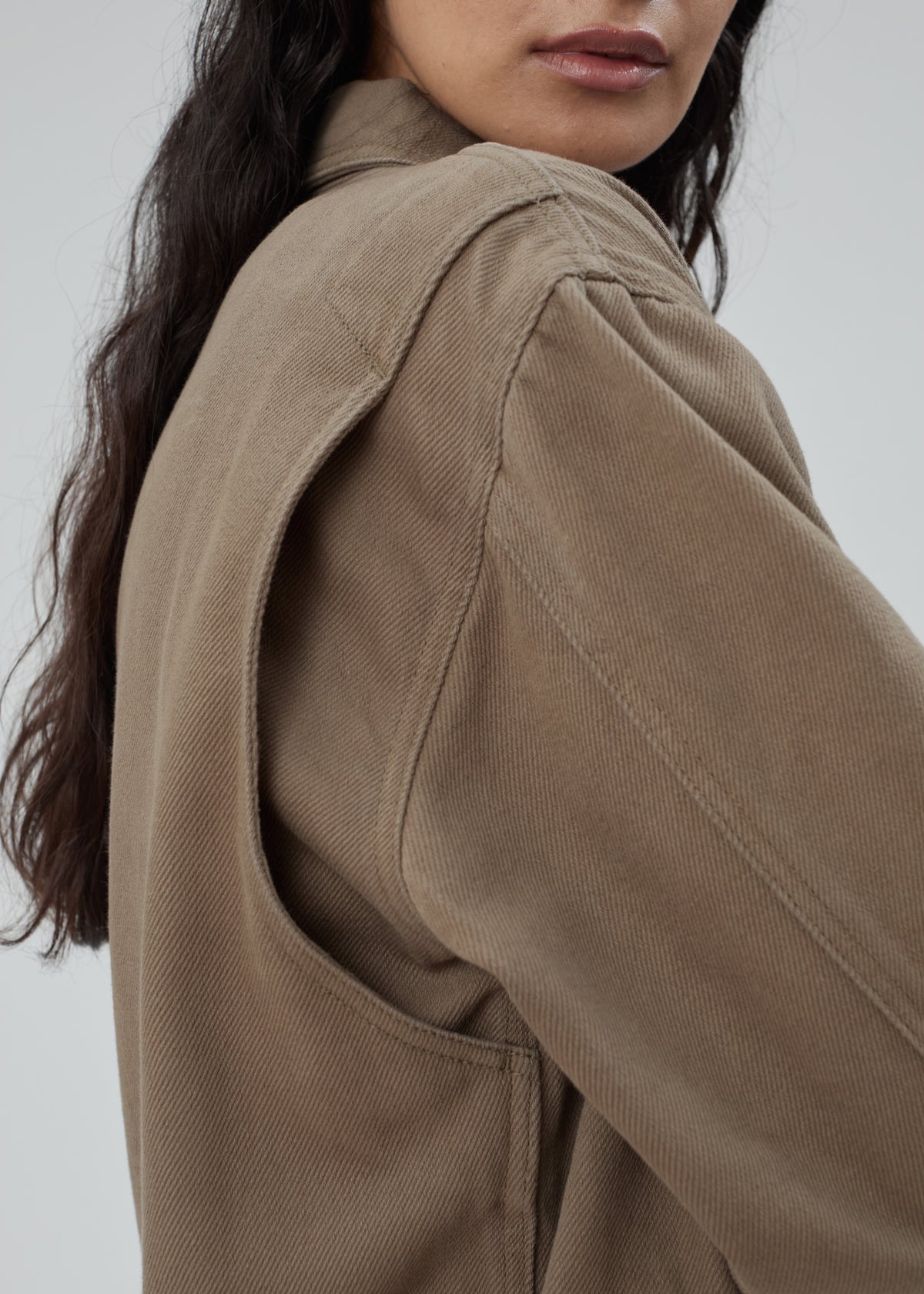 Close-up of a person wearing an olive green cotton denim Barn Jacket in Army Green featuring a back yoke overlay.