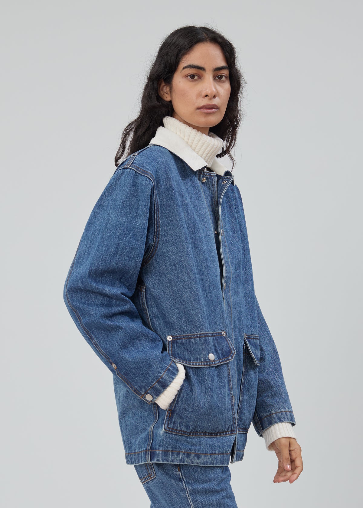 A person wears a Barn Jacket in Classic Blue with a white ribbed collar over a matching white turtleneck.
