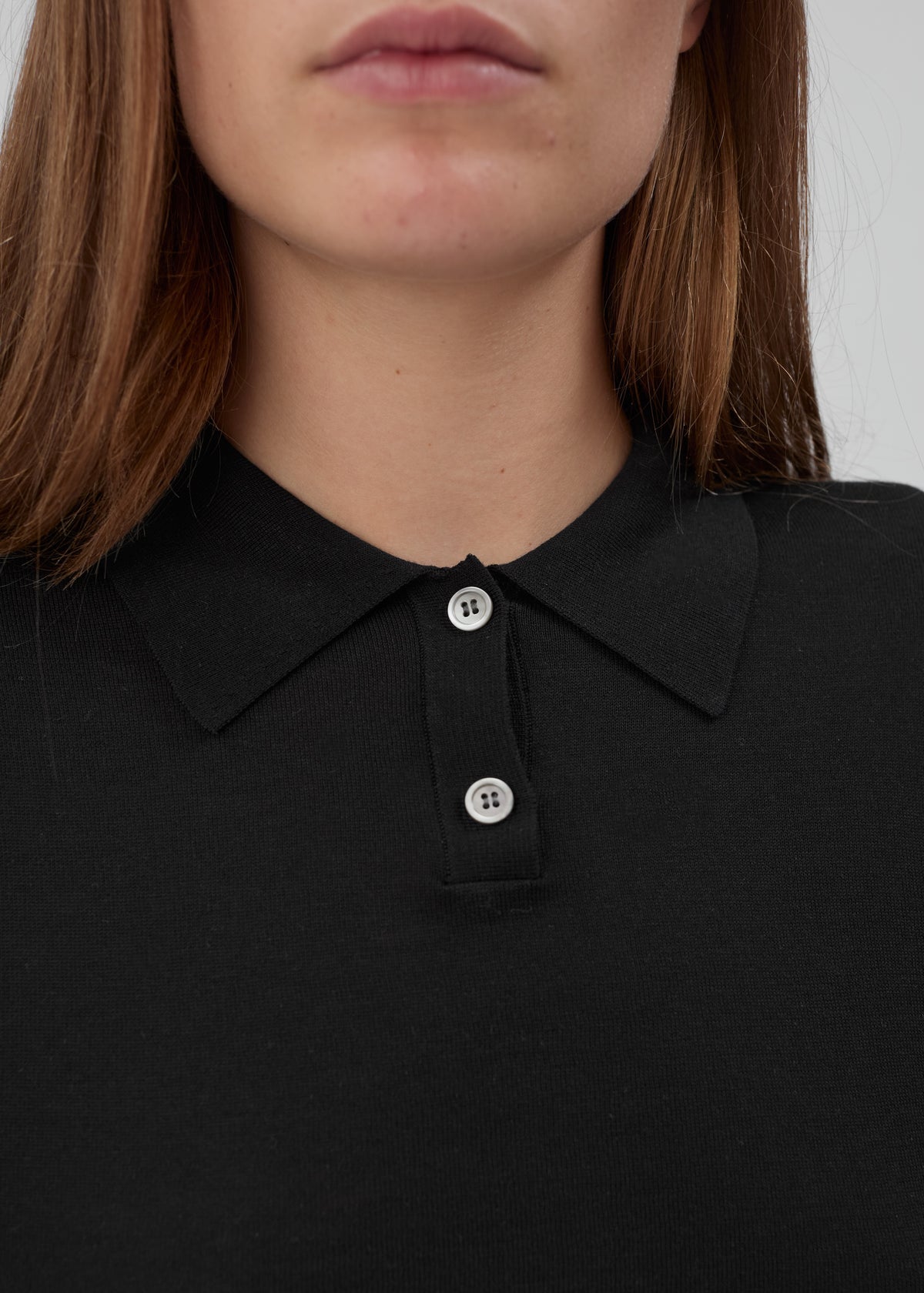 Close-up of a black Daughter Sweater Long Sleeve in a knit fabric with a collared neckline and two buttons.