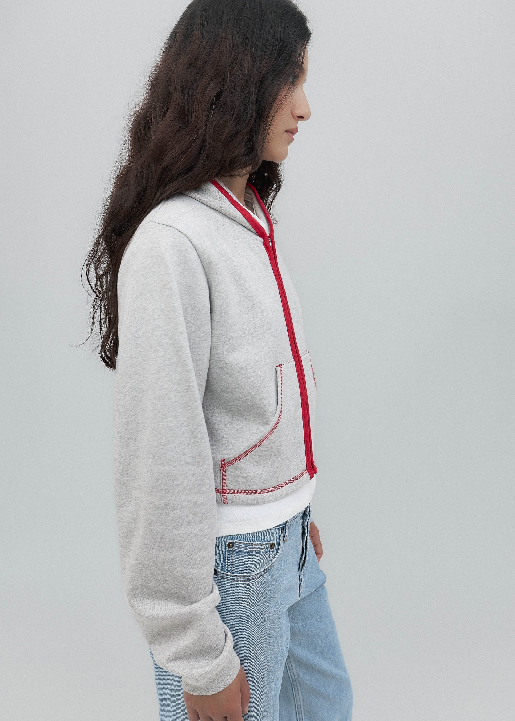 Person wearing a gray hoodie with red accents on a plain background