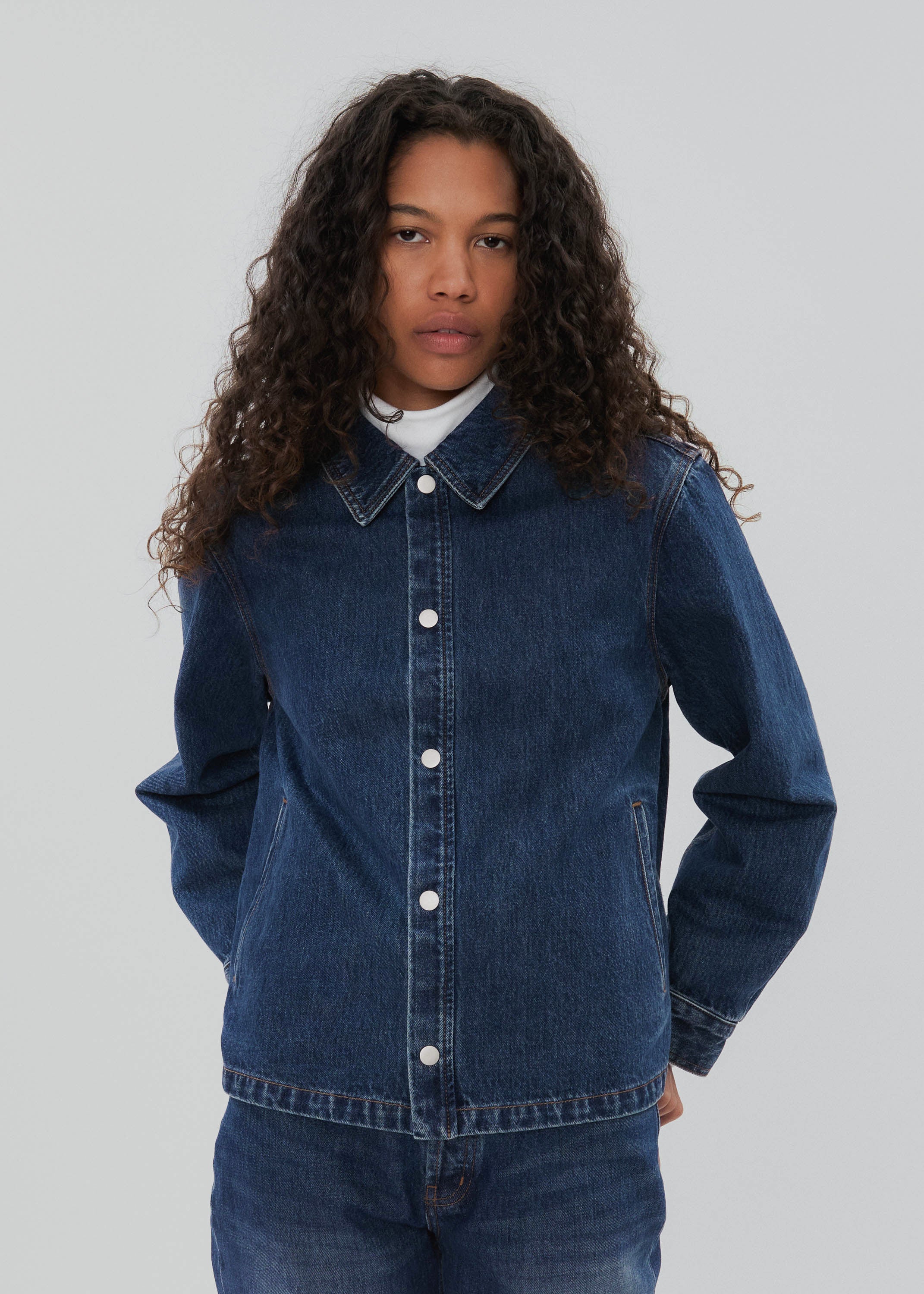 Person wearing a blue denim jacket on a plain background