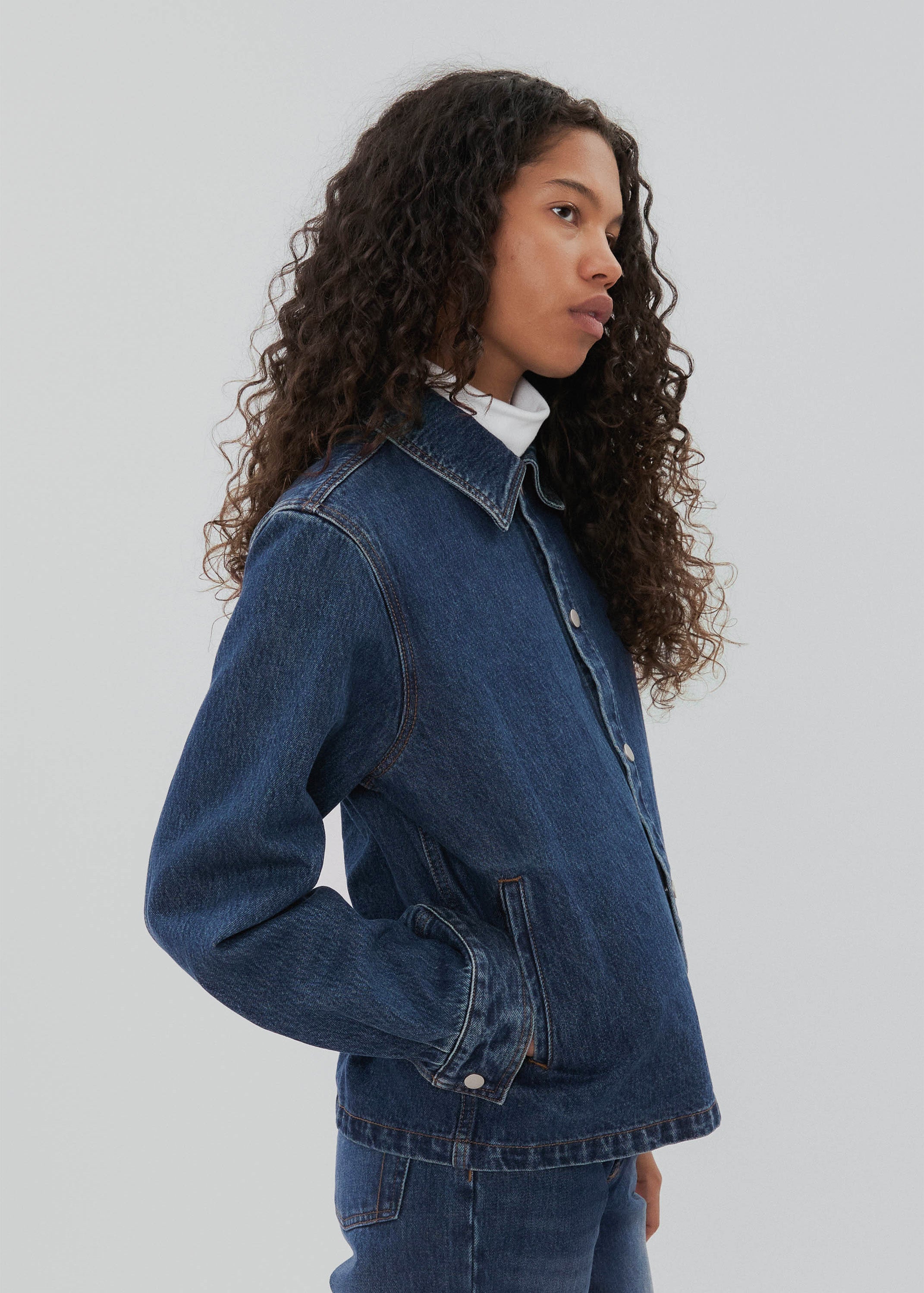 Woman wearing a blue denim jacket on a plain background